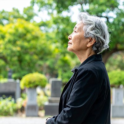 墓参りする高齢女性